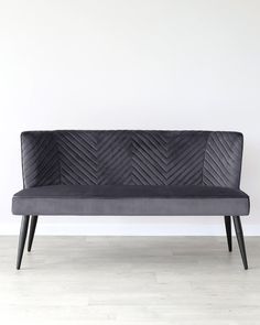 a gray couch sitting on top of a hard wood floor next to a white wall