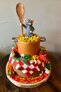 a birthday cake with a mouse in the pot on top of it and a wooden spoon