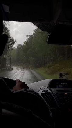 a man driving down a rain soaked road in the dark with trees on both sides