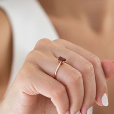 a woman's hand holding a ring with a garnet colored stone on it