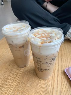 two iced coffees sitting on top of a wooden table