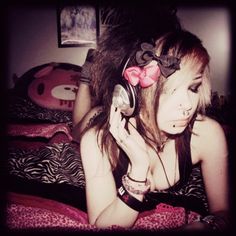 a woman laying on top of a bed with headphones in her ears and an animal print pillow behind her