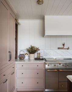 a kitchen with white cabinets and marble counter tops, along with brass pulls on the cabinet doors