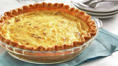 a pie sitting on top of a table next to a fork and bowl filled with food