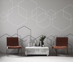 two chairs and a table in front of a wall with hexagonal shapes on it