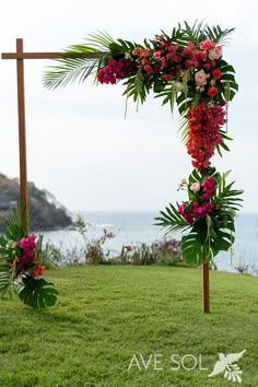 an outdoor wedding ceremony setup with flowers and greenery on the grass by the ocean