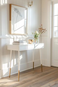 Bright and airy corner of a modern farmhouse with a sleek white console table, golden accents, and framed botanical art. Living Room With Table, Cozy Farmhouse Living Room, Living Room Tables, Cozy Farmhouse