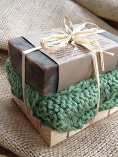 three wrapped gifts sitting on top of each other in green and brown colors with ribbons