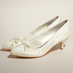 a pair of white shoes with bows on the toe and heel, all covered in lace