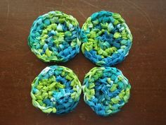 four crocheted coasters sitting on top of a wooden table