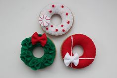 three decorated doughnuts sitting next to each other on a white surface with red and green decorations