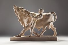 a statue of a man riding on the back of a horse next to a cow