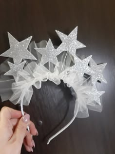 a hand is holding a white headband with stars on it and some tulle