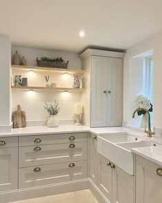 a white kitchen with lots of cabinets and counter top space in the center is lit by recessed lights