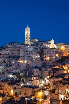 Historic hilltop town lit up at night with a prominent church tower under a deep blue sky. Italy Photo Ideas, Matera Italy, Cave City, Stone City, San Giacomo