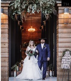 a bride and groom are walking out of the barn