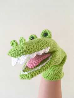 a crocheted hand with a green and white alligator's head