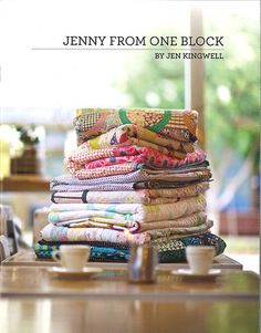 a stack of clothes sitting on top of a wooden table next to a cup and saucer