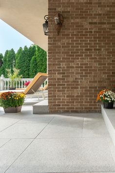 two flower pots sitting on the side of a brick wall next to a white bench