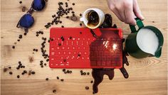 a person pouring coffee into a red keyboard