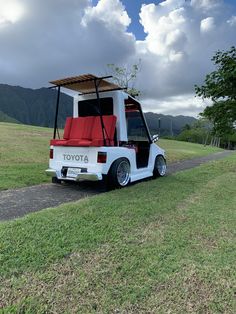 a white golf cart with red seats parked on the side of a road in front of mountains