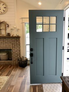 a blue front door in a house with wood floors and a clock on the wall