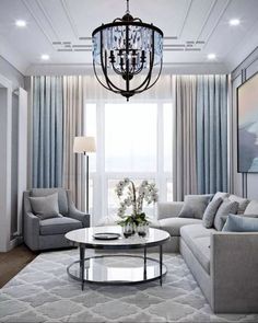 a living room filled with furniture and a chandelier hanging over the top of a coffee table