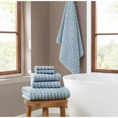 towels stacked on stool next to bathtub in bathroom