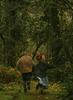 a man and woman are running through the woods