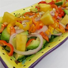 a yellow plate topped with lots of veggies and sliced up fruit on top of it