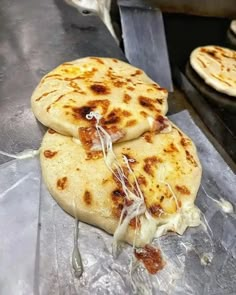 three flat bread pizzas sitting on top of a metal counter next to each other