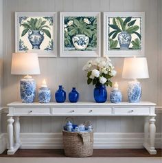 three blue and white vases sitting on top of a table next to two lamps