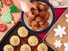 a person reaching for some cookies on a tray next to other desserts and christmas decorations