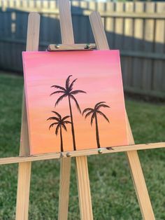 an easel with a painting of palm trees on it