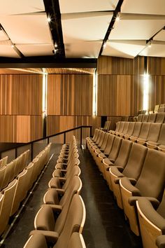 an empty auditorium with rows of seats and wood paneling on the wall behind it