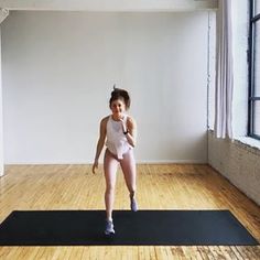 a woman is standing on a yoga mat in an empty room