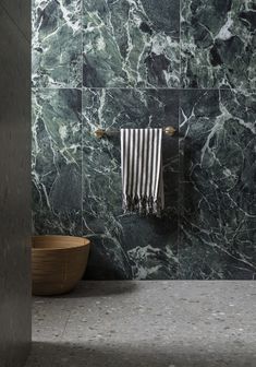 a green marble bathroom with a wooden bowl and towel rack on the wall next to it