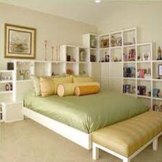 a bed sitting in the middle of a bedroom next to a book shelf filled with books