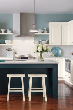 two stools sit in front of the kitchen island with white flowers on it and blue walls