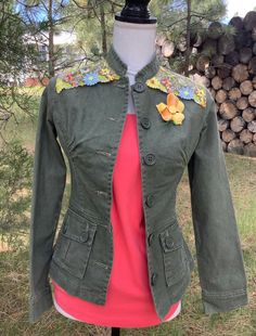 Women's green denim jacket, fitted, back peplum embellished with embroidered tulle of yellow, blue and green flowers and eaves. I have also added a vintage enameled yellow flower with green stem. Size extra-small, measures 16" across chest with button closed.  This would make a beautiful gift for the woman who likes unique, one-of-kind pieces!  Spot clean only!! Vintage Embroidered Denim Jacket For Spring, Vintage Cotton Outerwear For Spring, Fitted Green Cotton Outerwear, Green Cotton Denim Jacket For Fall, Fitted Green Outerwear For Spring, Green Spring Outerwear With Buttons, Fitted Cotton Denim Jacket With Buttons, Fitted Denim Jacket With Floral Embroidery For Summer, Spring Cotton Outerwear With Floral Applique