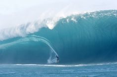 a man riding a wave on top of a surfboard in the middle of the ocean