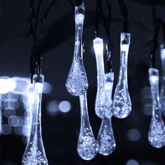 several glass vases hanging from strings with lights in the background