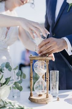 the bride and groom are holding hands over an hourglass