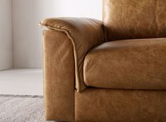 a brown leather couch sitting on top of a rug