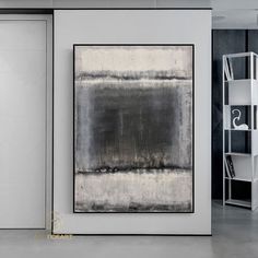 an abstract painting hangs on the wall next to a bookshelf and shelving unit