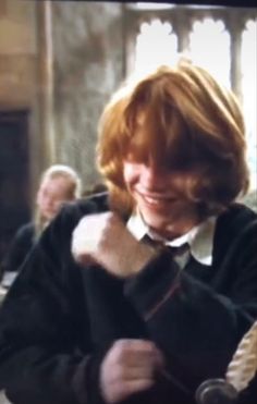 a woman with red hair wearing a harry potter robe and holding a wand in her right hand