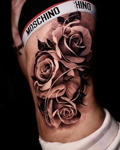 a woman's stomach with tattoos on it and roses tattooed on the side of her body