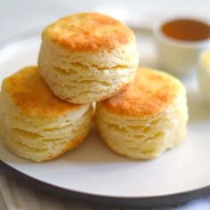 three biscuits stacked on top of each other on a white plate next to saucers