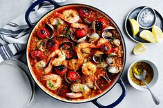 a large pot filled with seafood next to bowls of dipping sauces and lemon wedges