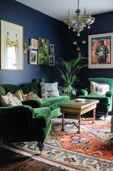 a living room with blue walls and green couches, rugs and pictures on the wall